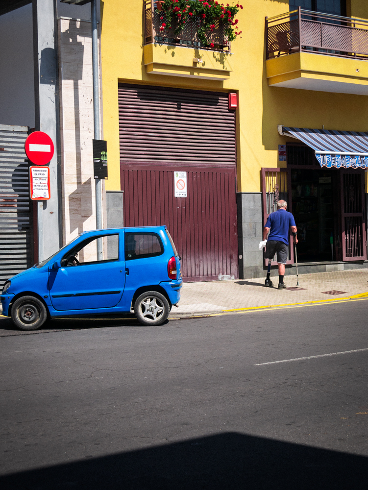 Homme avec une béquille et une jambe en moins sortant d'une voiture bleu
