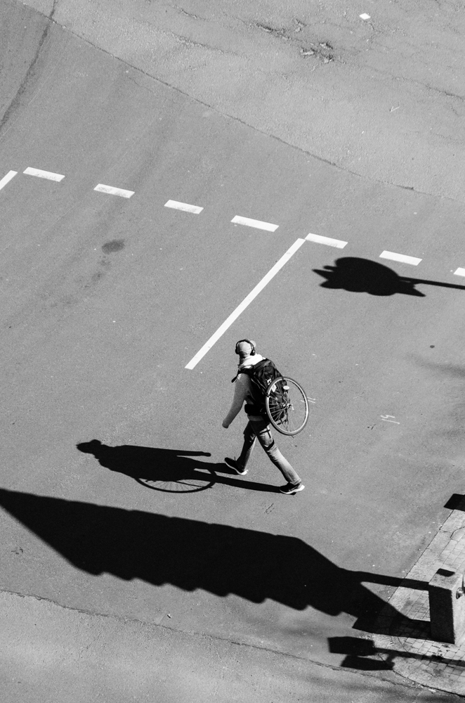 Un homme traverse la rue, une roue de vélo dans le dos