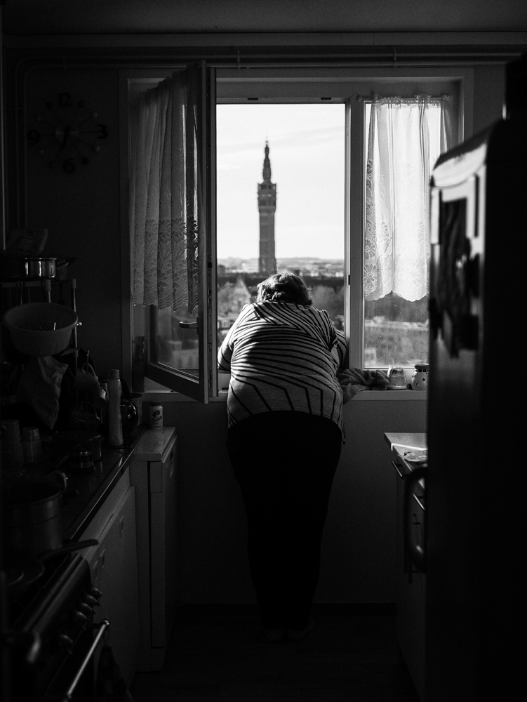 Photo d'une de dos, regardant par la fenêtre, avant en arrière plan le beffroi de la ville de Lille