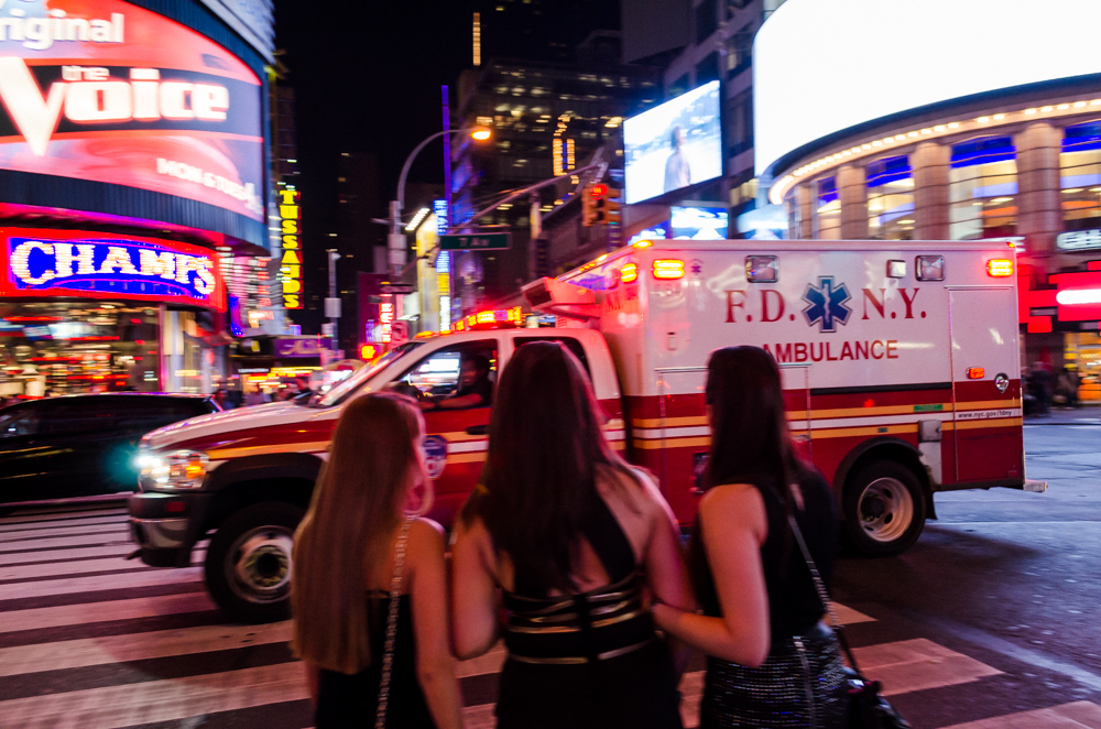 Time Square à New York, USA, ambulance passent devant des femmes en tenue de soirée
