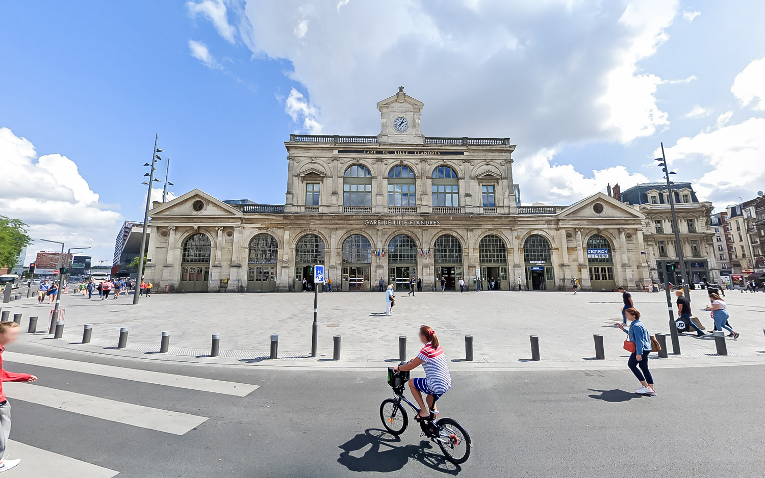 Femme en vélo devant la gare Lille Flandres