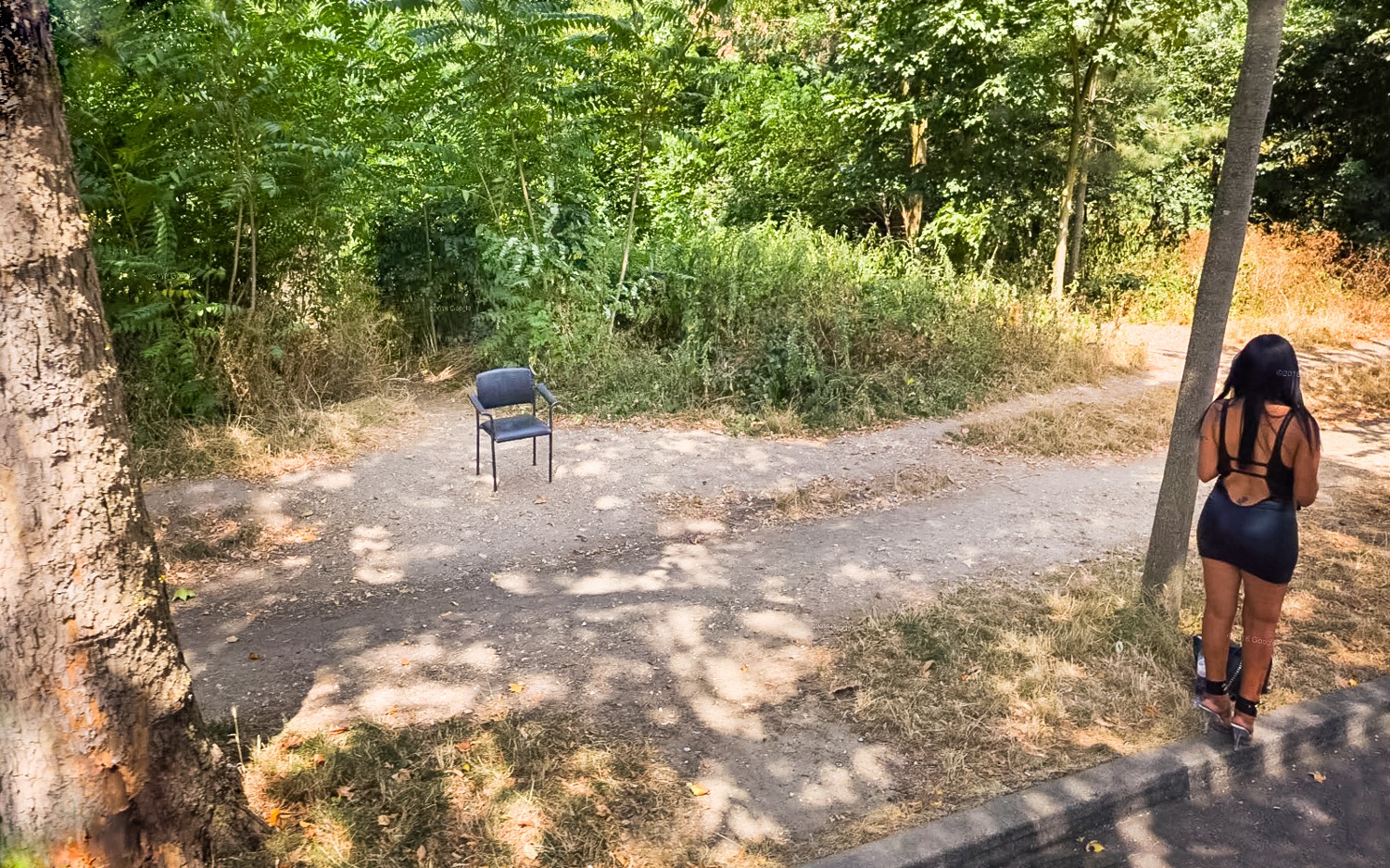 Une prosituée attend debout sur le trottoir, laissant sa chaise vide